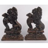 Two Victorian cast iron, black painted doorstops in the form of lions rampant on a plinth base,