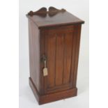An Edwardian walnut bedside cabinet, the panelled door opening to reveal two shelves,