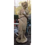 A large composition garden statue of a classical lady, scantily clad, on a circular plinth base,
