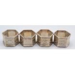A set of four hexagonal section silver napkin rings with chased floral and fern decoration,