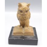 A gilt metal figure of a owl perched on an open book, early 20th century, with glass eyes,
