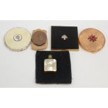 Four compacts and a perfume bottle.