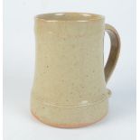 A Leach pottery cream glazed mug, impressed mark to base, height 11.9cm.