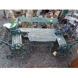 A green painted cast iron garden set, comprising of a table and two small matching benches,