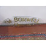 An oval plate glass sign, gilt painted 'T.M.