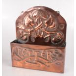 An Art Nouveau copper letter rack, the arched back with stylised floral motifs,