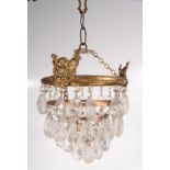 A gilt metal and cut glass ceiling shade, early 20th century, surmounted by three seated cherubs,