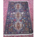 An Afghan Belouch rug, the indigo field with three brown lobed medallions,