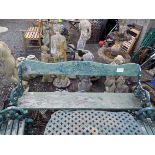 A green painted cast iron garden bench, with a shaped carved wood back and solid rectangular seat,