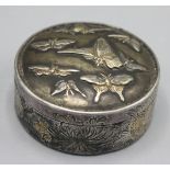 A Japanese white metal pill box, the circular hinged cover decorated with moths,