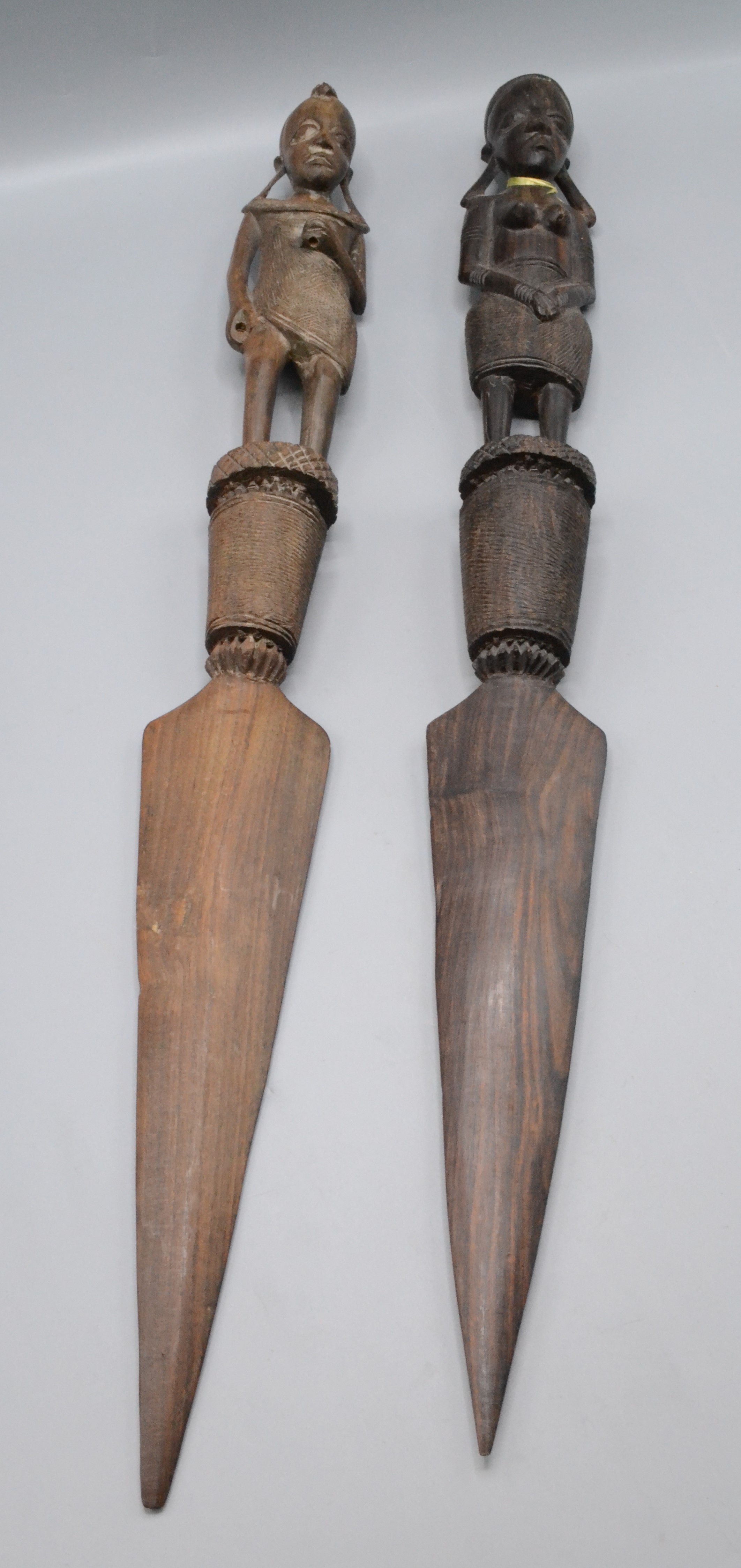 Two African carved wood daggers. each handle in the form of a tribal figure, length 61cm.