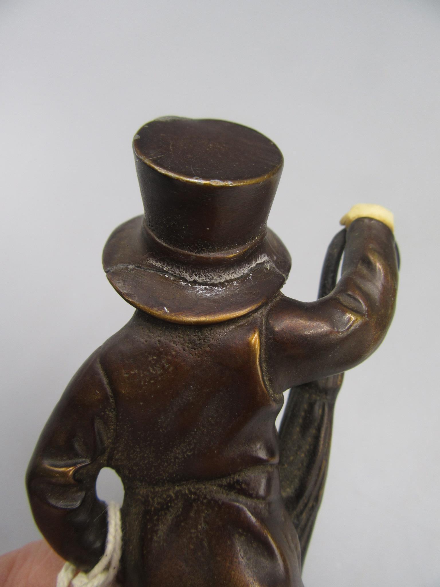 A bronze figure, probably the Artful Dodger, wearing a top hat and raised on a black marble base, - Image 4 of 4