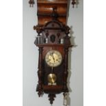 A Vienna walnut wall clock, 19th century, with three finials flanking a central portrait mask,