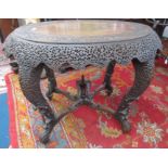 A Burmese hardwood centre table, 19th century, the oval top carved with animals,