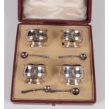 A set of four Mappin and Webb silver open salts with blue glass liners and matching spoons, cased.