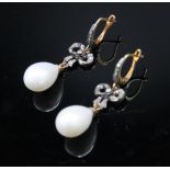 A pair of diamond bow and cultured pearl earrings.