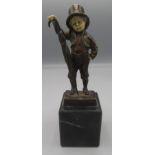 A bronze figure, probably the Artful Dodger, wearing a top hat and raised on a black marble base,