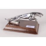 A chrome car mascot in the form of a Jaguar, mounted on a rectangular wooden plinth, height 8.