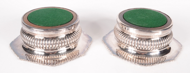A pair of silver plated wine coasters, each with a gadrooned body and turned wooden base,