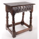 A carved oak joint stool in 17th century style with carved shaped frieze and low stretchers.