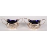 A pair of Edwardian silver embossed open salts with blue glass liners. 2oz.