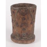 An African wooden mortar, with applied metal abstract decoration, height 29cm, diameter 20cm.
