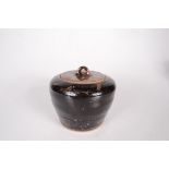 A studio pottery tenmoku glaze jar and cover, with a ribbed, tapering body, height 12cm,