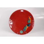 A large Poole Pottery shallow dish, the red ground with polychrome abstract design, diameter 39.5cm.