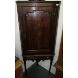 A George III oak corner cupboard on stand, the arched panelled door opening to reveal four shelves,