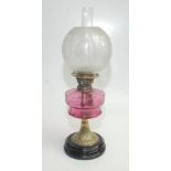 A brass and cranberry glass oil lamp, early 20th century, height 58.5cm.