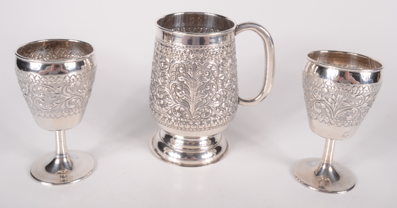 A United Arab Emirates repousse decorated mug and a pair of similar stemmed cups, 414g.