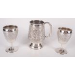 A United Arab Emirates repousse decorated mug and a pair of similar stemmed cups, 414g.