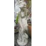 A large composition garden statue of a semi clad classical maiden, on a circular plinth base,