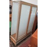A oak glazed shop display cabinet, early 20th century, with a pair of frosted glass doors,