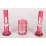 A pair of Mary Gregory cranberry glass bud vases, height 16cm and a similar mug, height 9cm.