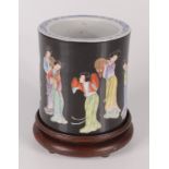 A Chinese famille noir porcelain circular brush pot, decorated with female musicians,