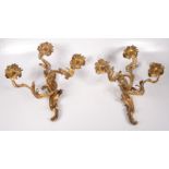 A pair of Rococo style gilt metal three branch wall lights,