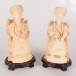 A pair of Chinese resin figures of a seated emperor and his wife, on hardwood stands, height 22cm.