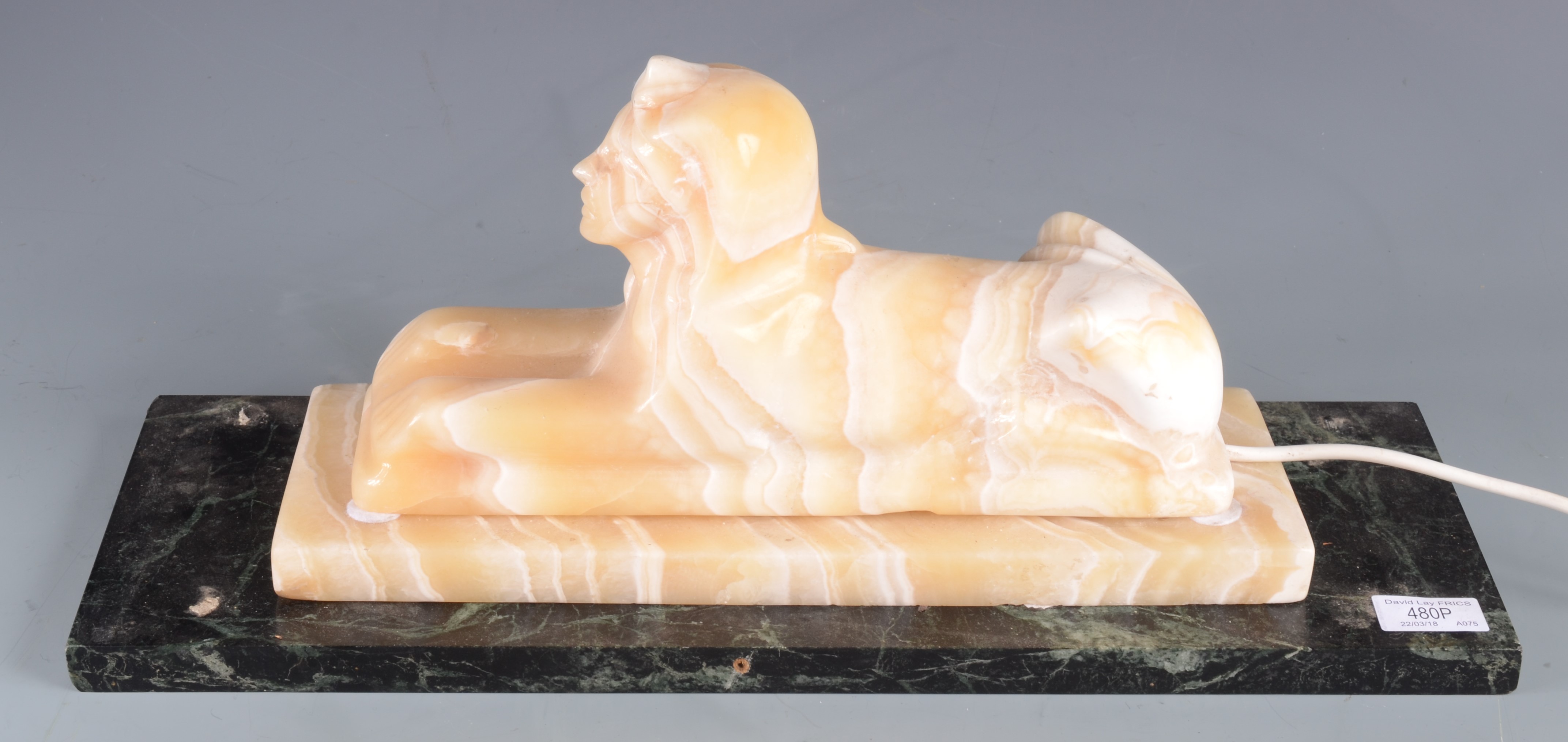 An alabaster lamp in the form of a sphinx, on a marble base, height 21cm, width 51cm, depth 17.7cm.