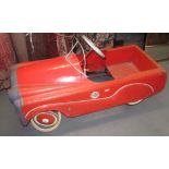 A child's red painted metal pedal car, with black rubber wheels, height 43cm, length 89cm,