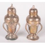 A pair of silver Arts and Crafts inverted pear form pepper pots each with three flowering applied