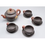 A Chinese Yixing pottery tea set, comprising a teapot and four cups and saucers,