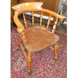 A late Victorian smokers bow captain's armchair, with spindle filled back and solid seat,