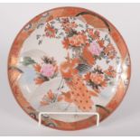A Japanese Kutani plate, late 19th century, decorated with a peacock beside a flowering tree,