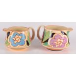 Two Clarice Cliff Bizarre Fantasque jugs, each hand painted with flowers amongst foliage,