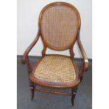 A Victorian beech armchair, with a rattan back and seat, on turned tapering legs,