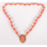 A pink coral necklace, at the centre a gold mounted coral portrait cameo.