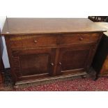 A Heals oak sideboard, with two frieze doors above two panelled doors on bun feet,