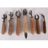 Seven wooden handled old tin openers.