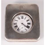 A nickel eight day travelling timepiece in engine turned silver mounted case.